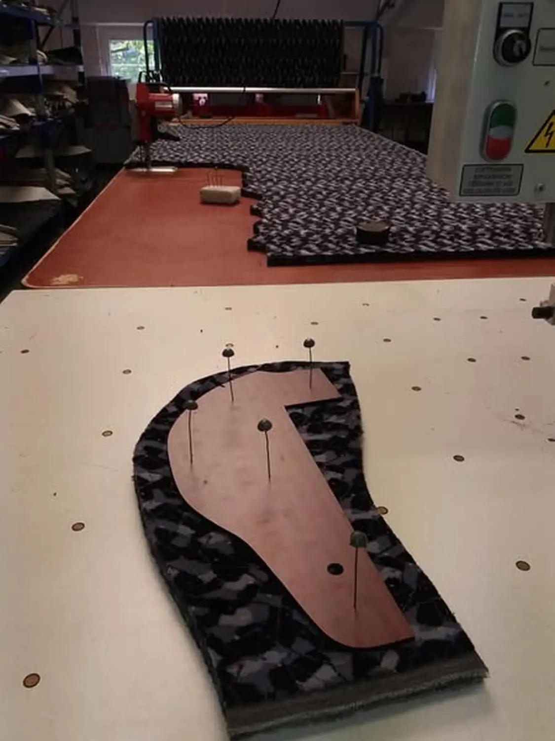 Die weiblichen Hände eines Möbeldesignmeisters schneiden ein Stück Schaumstoff nach einem vorgegebenen Muster.